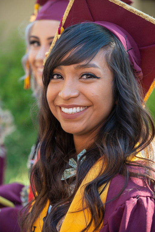 smiling young woman in grad cap and gown