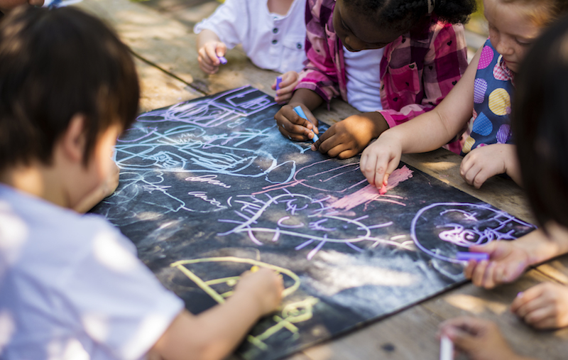 children drawing with colored markers on wooden table 