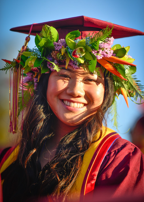 smiling young woman in grad cap and decorative leis