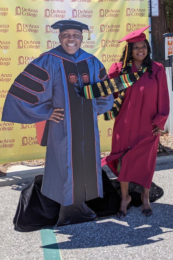 young woman in cap and gown with cutout of President Holmes