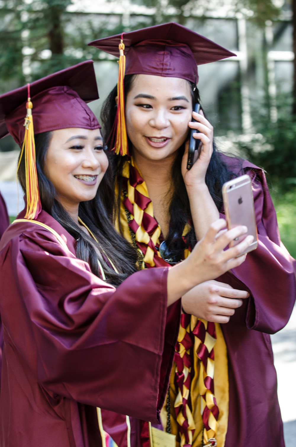 two graduates looking at phone