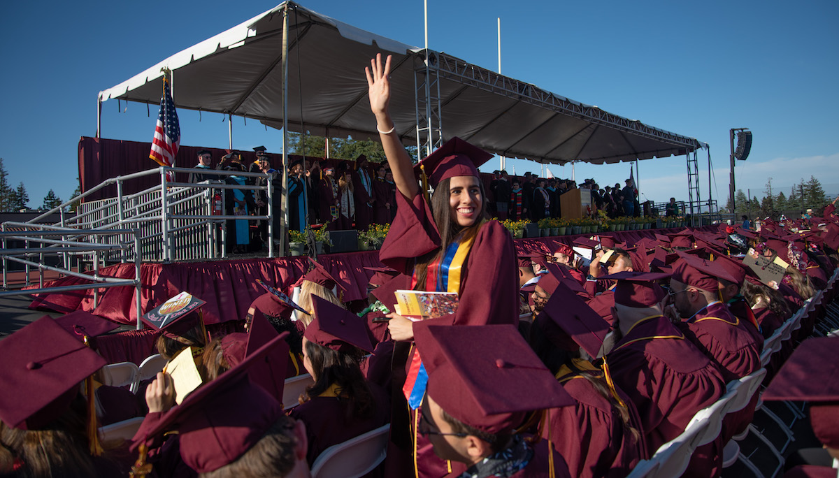 student waving in crowd of graduates