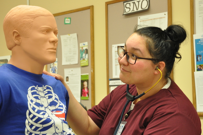 smiling student with practice mannequin