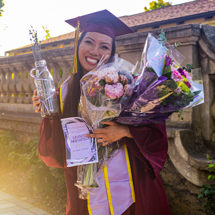 smiling student with lavender grad sash and flowers