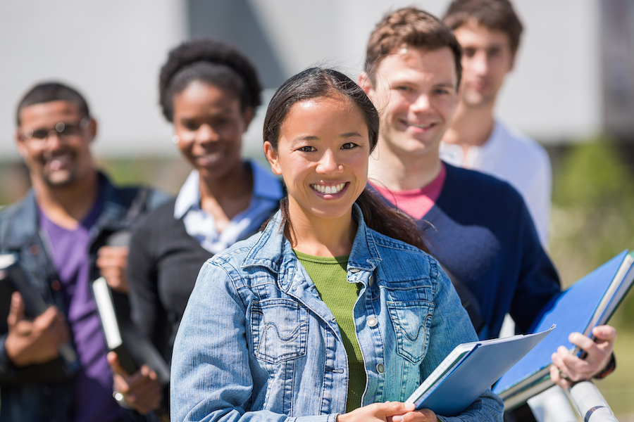 young woman in denim jacket standing in front of other smiling students