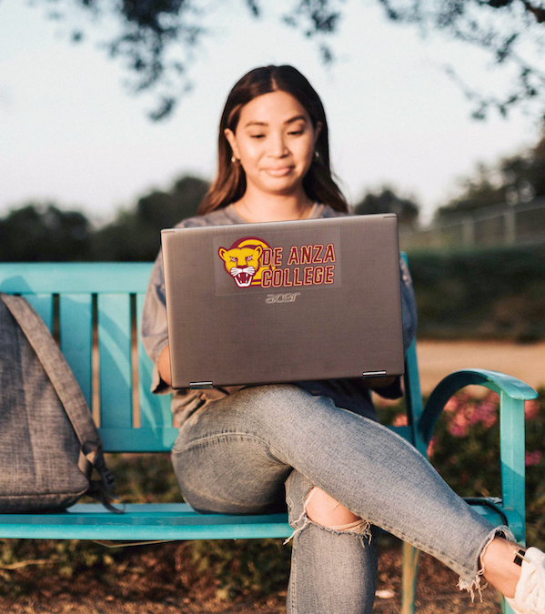 young woman on bench with laptop