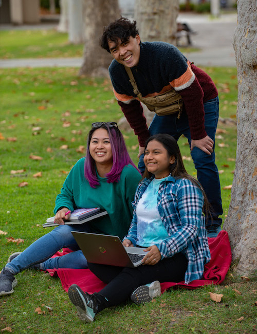 young man standing next to two seated young women