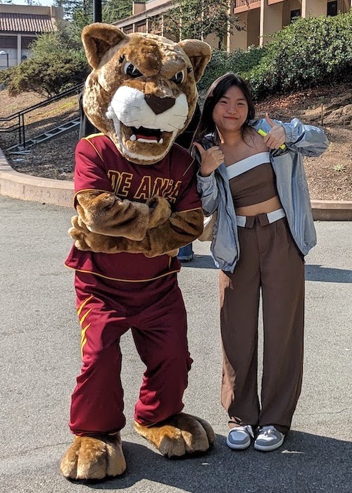 Roary the Mountain Lion with a student, who's gesturing with both thumbs up