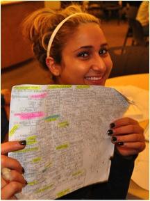 Female student smiling holding up testing notes with colorful highlighting